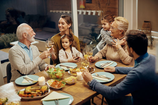 Familia sentada ao redor de uma mesa preparada para uma celebração de fim de ano e brindando